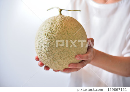 A woman offering a muskmelon (produced in Kumamoto Prefecture) A woman offering a muskmelon (produced in Kumamoto Prefecture) 129867131