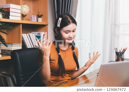 Homeschool Asian girl student learning virtual internet online class from school teacher by remote meeting. Female teaching math by headphone. education concept. student with computer study at school 129867472