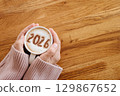 woman in cozy warm sweater enjoying hot coffee. On milk foam numbers 2026. New Year concept 129867652