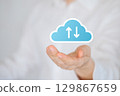 Hand holding digital cloud icon with upload and download arrows, symbolizing data transfer and cloud storage 129867659