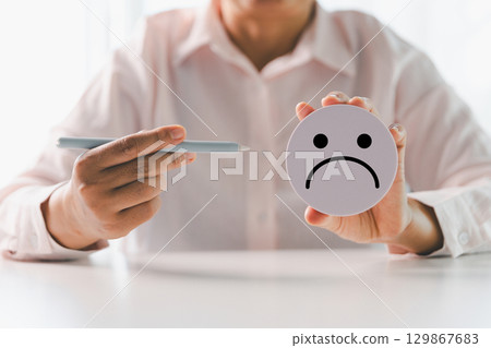 Close up customer hand choose sad face and blurred smiley face icon, Service rating, satisfaction concept. Negative feedback from client often reflects dissatisfaction with quality of service. 129867683