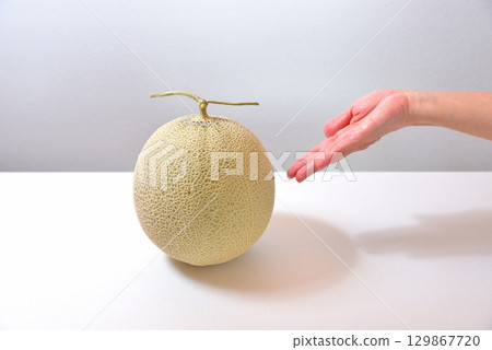A woman holds out her hand, offering a muskmelon (produced in Kumamoto Prefecture) A woman holds out her hand, offering a muskmelon (produced in Kumamoto Prefecture) 129867720