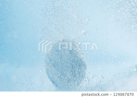 White effervescent tablet dissolving in glass of water over blue background. Acetylsalicylic acid painkiller tablet. Aspirin effervescent pill in water. White effervescent tablet dissolving in glass of water over blue background. Acetylsalicylic acid painkiller tablet. Aspirin effervescent pill in water. 129867870