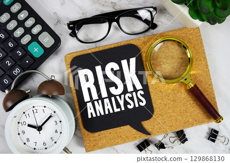 Risk Analysis text with Calculator, alarm clock and magnifying glass on marble background 129868130