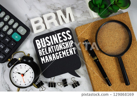 BRM Business Relationship Management text with Calculator, alarm clock and magnifying glass on marble background 129868169