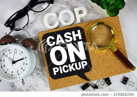 COP Cash On Pickup text with alarm clock and magnifying glass on marble background 129868200