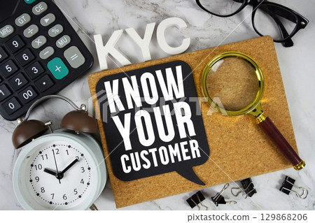 KYC Know Your Customer text with Calculator, alarm clock and magnifying glass on marble background KYC Know Your Customer text with Calculator, alarm clock and magnifying glass on marble background 129868206