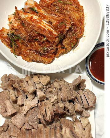 Suyuk, a traditional Korean dish of boiled pork slices, tender and juicy, often served with salted shrimp sauce, garlic, and ssamjang. Perfect for wrapping in lettuce for a flavorful, balanced bite. 129868837