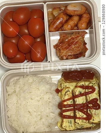 A colorful dosirak lunchbox filled with neatly arranged rice, savory protein, and assorted side dishes. A portable feast that captures the essence of authentic Korean home-style cooking. 129868980