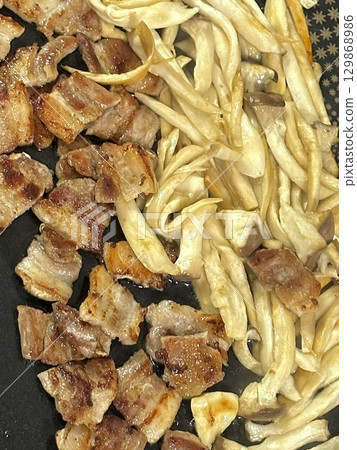 Juicy grilled samgyeopsal paired with savory mushrooms and tangy, sizzling kimchi, creating a perfect balance of rich, earthy, and spicy flavors in every delicious, mouthwatering bite. 129868986
