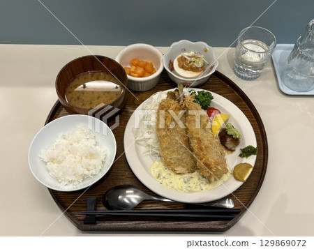 Crispy tonkatsu, a Japanese-style breaded and deep-fried pork cutlet, served with shredded cabbage and drizzled with savory sauce. A delightful balance of crunchy texture and juicy meat. 129869072