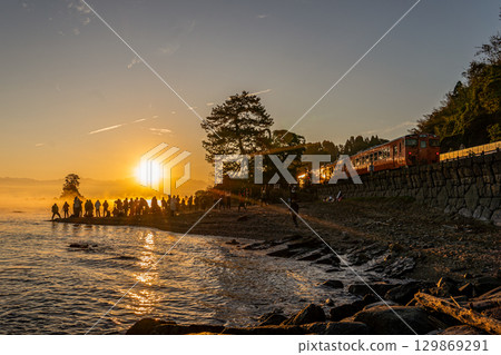 Trains and people bathed in the first sunrise of the year [Amaharashi Coast] 129869291