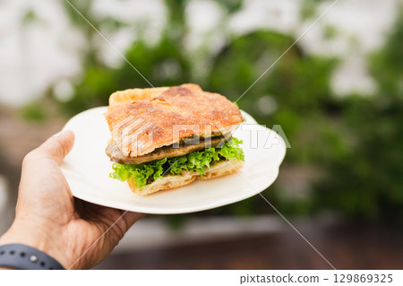 Man bringing fresh focaccia sandwiches on a white plate. 129869325