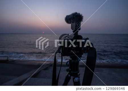 Photographing the sunset with a camera and tripod Photographing the sunset with a camera and tripod 129869346