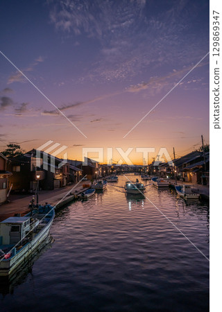 A boat sailing through the port town at dusk [Shinminatouchi River] 129869347