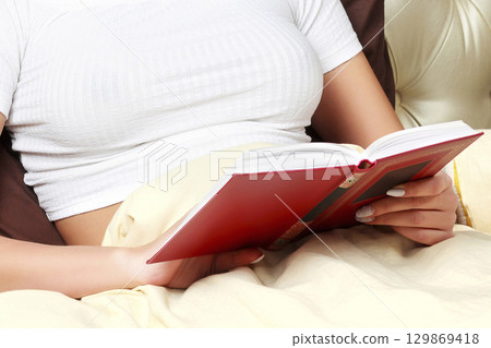 Young woman reading a book in bed Young woman reading a book in bed 129869418