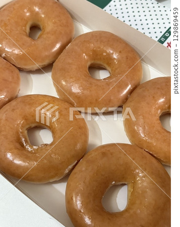 A classic glazed donut with a soft, fluffy texture and a sweet, glossy coating. Perfectly balanced between light and sugary, making it an irresistible treat for any time of the day. 129869459