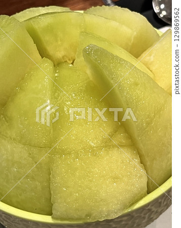 Refreshing melon bingsu with fluffy shaved ice topped with sweet, juicy melon balls, offering a perfect combination of cool, fruity, and creamy flavors in every delightful summer bite. 129869562