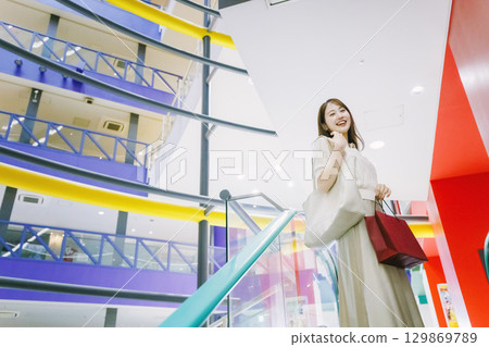 一位女士在百貨公司搭乘自動扶梯 129869789