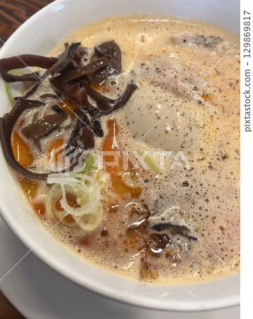 A steaming bowl of ramen with rich broth, tender noodles, sliced pork, boiled egg, nori, and fresh green onions. A comforting and flavorful Japanese classic. 129869817