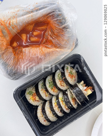 Spicy and chewy tteokbokki paired with fresh and flavorful kimbap rolls filled with rice, vegetables, and protein. A perfect Korean street food combination for a satisfying meal. 129869825