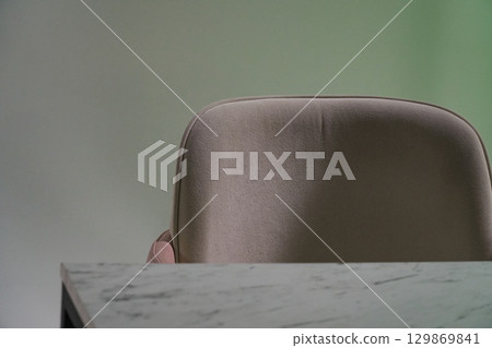 Back of an empty chair with soft pile cover, next to a blurred table surface with copy space on a gradient green background, artwork blank Back of an empty chair with soft pile cover, next to a blurred table surface with copy space on a gradient green background, artwork blank 129869841