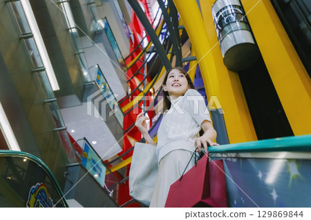 一位女士在百貨公司搭乘自動扶梯 一位女士在百貨公司搭乘自動扶梯 129869844