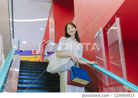 一位女士在百貨公司搭乘自動扶梯 129869915