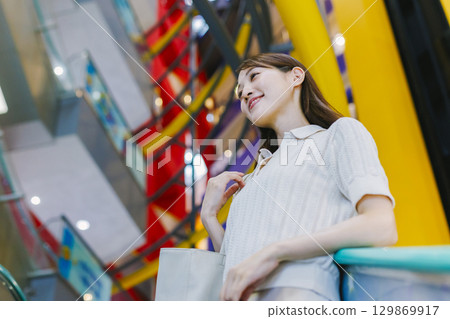 一位女士在百貨公司搭乘自動扶梯 129869917