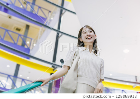 A woman riding an escalator in a department store A woman riding an escalator in a department store 129869918