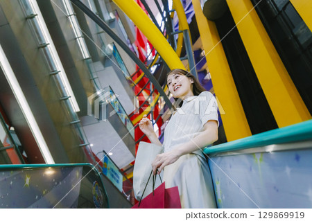 A woman riding an escalator in a department store A woman riding an escalator in a department store 129869919