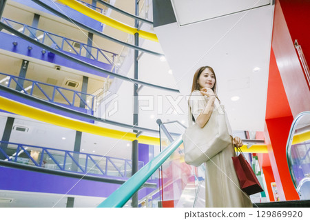 一位女士在百貨公司搭乘自動扶梯 129869920