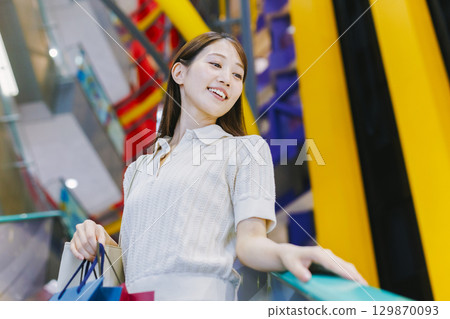 A woman riding an escalator in a department store A woman riding an escalator in a department store 129870093