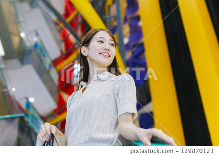 一位女士在百貨公司搭乘自動扶梯 129870121