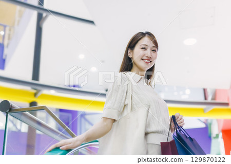 一位女士在百貨公司搭乘自動扶梯 一位女士在百貨公司搭乘自動扶梯 129870122