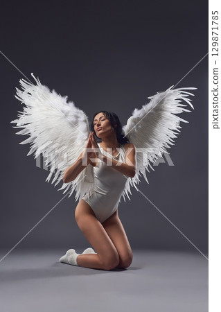 Graceful woman in underwear with feather wings praying to the God Graceful woman in underwear with feather wings praying to the God 129871785