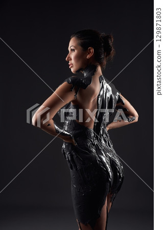 Naked woman with black body paint standing in studio 129871803