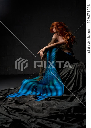 Lonely mermaid sitting on the rock with her head down Lonely mermaid sitting on the rock with her head down 129871998