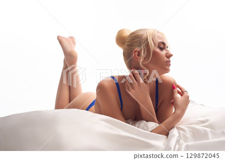 Sexual woman in lingerie lying on bed with white bed linen and touching her body 129872045