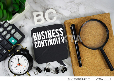 BC Business Continuity text with Calculator, alarm clock and magnifying glass on marble background BC Business Continuity text with Calculator, alarm clock and magnifying glass on marble background 129872295