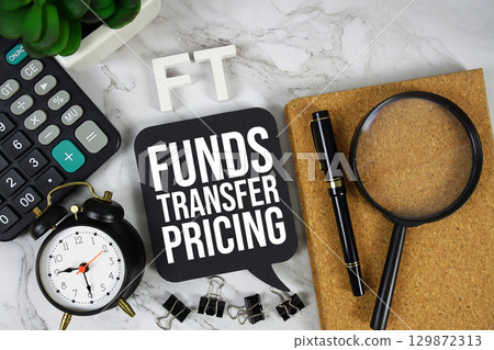 FT Funds Transfer text with Calculator, alarm clock and magnifying glass on marble background 129872313