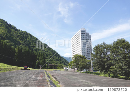 夏季滑雪勝地山腳下的度假公寓大樓和雪地修整機 夏季滑雪勝地山腳下的度假公寓大樓和雪地修整機 129872720