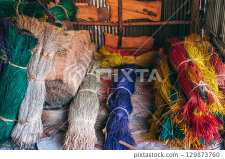 multicolored dry dyed reeds lie in piles at warehouse for the production of traditional woven mats in a Vietnamese village in Vietnam 129873760