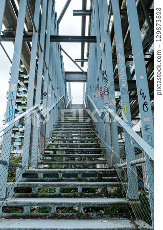 Staircase leading upward through industrial structure, surrounded by metal beams and urban graffiti, showcasing urban exploration and architectural design concepts. Strijp S district in Eindhoven 129873898