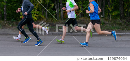 Four male runners running marathon in city park Four male runners running marathon in city park 129874064