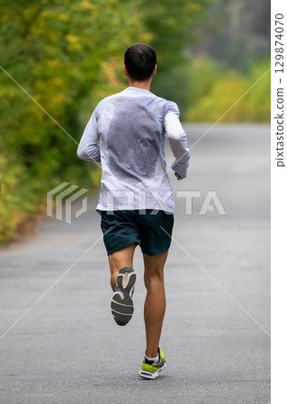 Runner with sweat-soaked back running marathon race Runner with sweat-soaked back running marathon race 129874070