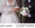 Young couple at the wedding exchanges engagement rings 129874498