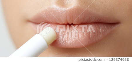 Lip balm application on close up face showing beauty and makeup routine with foundation blending for smooth cosmetic care and natural look 129874958