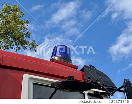 A red fire truck equipped with an emergency siren on a summer day. High quality photo 129875846