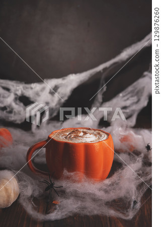 Halloween pumpkin latte with whipped cream and spooky decor on a wooden background. Halloween pumpkin latte with whipped cream and spooky decor on a wooden background. 129876260